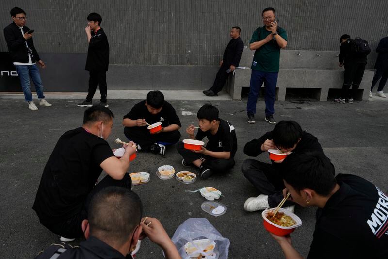 Workers take a lunch break during Auto China 2024 in Beijing, Thursday, April 25, 2024. Global automakers and EV startups unveiled new models and concept cars at China's largest auto show on Thursday, with a focus on the nation's transformation into a major market and production base for digitally connected, new-energy vehicles. (AP Photo/Ng Han Guan)