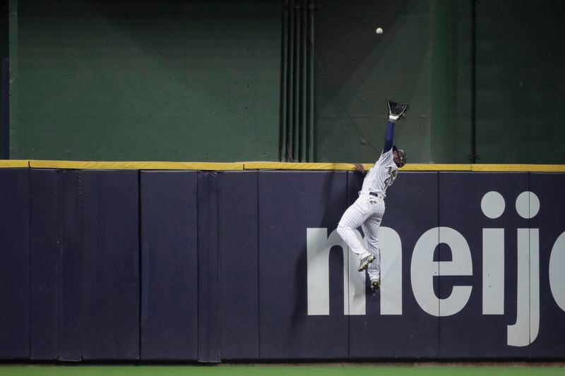 Milwaukee Brewers' Jackie Bradley Jr. makes a leaping catch at the wall on a ball hit by Atlanta Braves' Ozzie Albies during the seventh inning of a baseball game Saturday, May 15, 2021, in Milwaukee. (AP Photo/Aaron Gash)