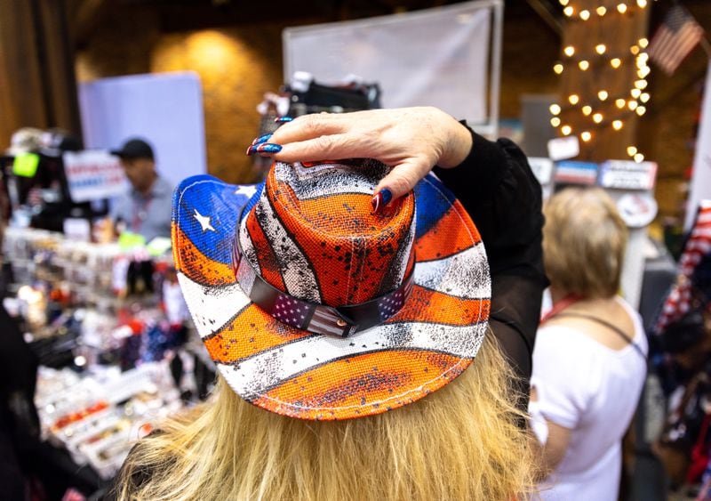 A person tries on a hat at the Georgia GOP convention in Columbus on Friday, June 9, 2023. (Arvin Temkar / arvin.temkar@ajc.com)