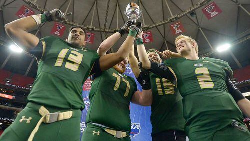 Grayson seniors Ishmail Abdul (13, L-R), Will Taylor (77), Jake Killian (15) and Chase Brice (2) hold their trophy up after beating Rowell during their Class AAAAAAA state title game at the Georgia Dome Saturday.
