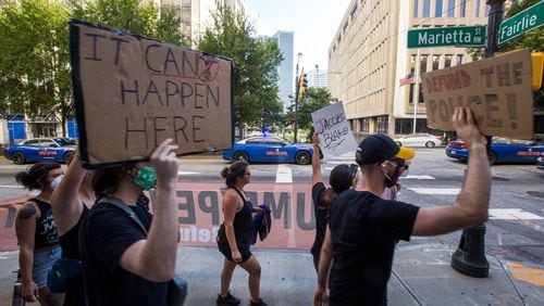 Protesters march past the Atlanta Police Department with heavy police presence as they march to the CNN Center in September.  (Jenni Girtman for The Atlanta Journal-Constitution)