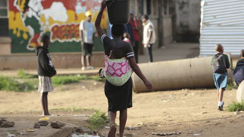 FILE - A woman carries a her baby and a bucket of water in Harare on April 6, 2020. A new study says an African woman is roughly 130 times more likely to die from pregnancy and childbirth complications than a woman in Europe or North America, the U.N. population fund reported Wednesday, April 17, 2024, as it decried widening inequality in sexual and reproductive health and rights worldwide. (AP Photo/Tsvangirayi Mukwazhi, File)