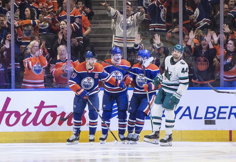 San Jose Sharks' Marc-Edouard Vlasic (44) skates past as Edmonton Oilers' Connor McDavid (97), Zach Hyman (18) and Adam Henrique celebrate a goal during the first period of an NHL hockey game in Edmonton, Alberta, on Monday, April 15, 2024. (Jason Franson/The Canadian Press via AP)