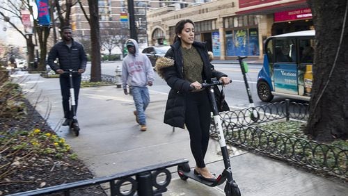 A woman rides a Bird scooter along the sidewalk on Peachtree Street in Atlanta’s Midtown community, Friday, January 4, 2019. (ALYSSA POINTER/ALYSSA.POINTER@AJC.COM)