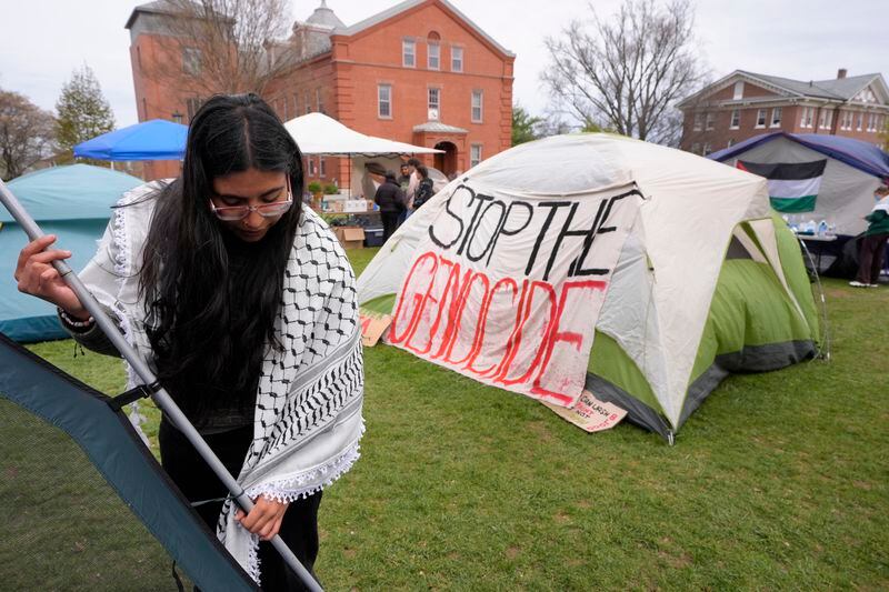 A woman wears a keffiyeh, left, while setting up a tent at an encampment of tents on the campus of Tufts University, Tuesday, April 30, 2024, in Medford, Mass. Tufts University students set up the encampment as part of a protest against the war in Gaza. (AP Photo/Steven Senne)