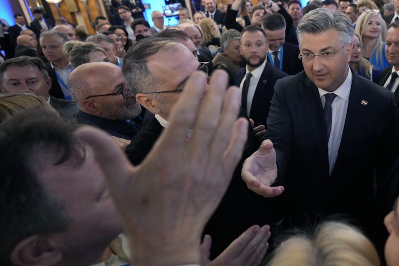 Prime Minister incumbent Andrej Plenkovic, right, shakes hands with his supporters after claiming victory in a parliamentary election in Zagreb, Croatia, Thursday, April 18, 2024. Croatia's governing conservatives convincingly won a highly contested parliamentary election Wednesday, but will still need support from far-right groups to stay in power, according to the official vote count. The election followed a campaign that centered on a bitter rivalry between the country's president and prime minister. (AP Photo/Darko Vojinovic)