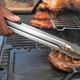 Eric Farley, of the Boys and Girls Club, sears a piece of grilled pork at the World Championship Barbecue Cooking Contest, Friday, May 17, 2024, in Memphis, Tenn. (AP Photo/George Walker IV)