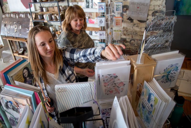 Christy Weiss (L) and Jody Caldwell look over cards during Small Business Saturday at Garage Door Studio at Avondale Estates. STEVE SCHAEFER / SPECIAL TO THE AJC