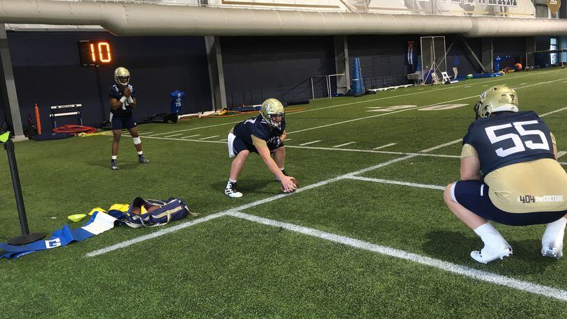 Georgia Tech offensive lineman Mikey Minihan works on his shotgun snaps with quarterback James Graham under the eye of center Kenny Cooper (No. 55) at the Yellow Jackets' first spring practice, March 3, 2020, at the Brock Football Practice Facility. (AJC photo by Ken Sugiura)