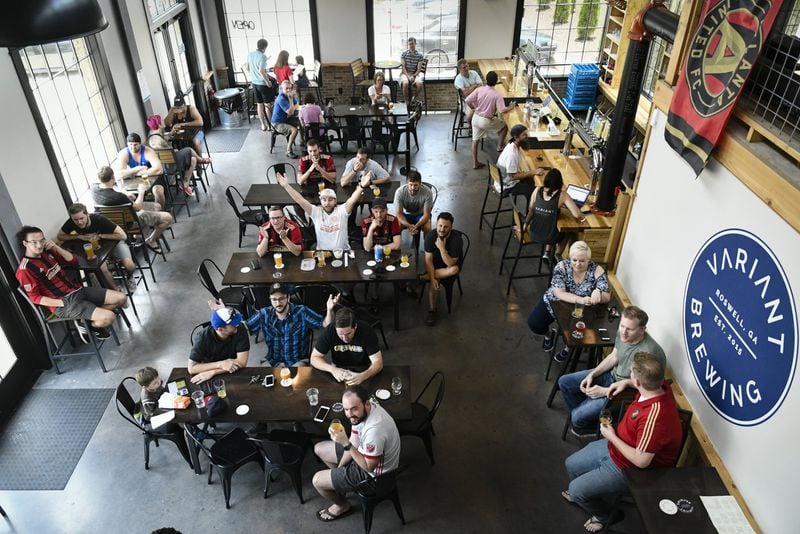 Alec Wenzel (center) throws up his arms as he reacts while he and other Atlanta United fans watch a soccer game on TV at Variant Brewing on June 9. Both Variant and Gate City are breweries located in Roswell, making it a beer destination town. CONTRIBUTED BY JOHN AMIS
