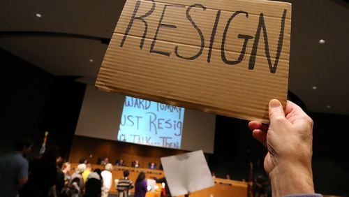 February 28, 2017, Lawrenceville: Rachel Theus holds a resign sign while more protesters demand the resignation of Tommy Hunter, the District 3 leader that recentlyÂ called U.S. Rep. John Lewis aÂ âracist pigâÂ on Facebook, during the Gwinnett County Board of Commissioners public hearing session on Tuesday Feb. 28, 2017, in Lawrenceville.   Curtis Compton/ccompton@ajc.com