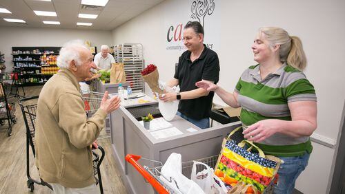 On the north end of Sandy Springs, in 2018, Community Assistance Center volunteers Mort Epstein, center, and Lori Proctor, right, help customer Alexander Boguslavskiy checks out at the food pantry. (JASON GETZ/SPECIAL TO THE AJC)