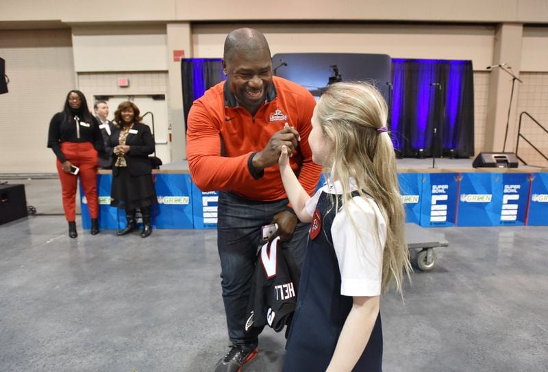 Ovie Mughelli, former Atlanta Falcons fullback, high-fives Mary Minson, 8, a student at Christ the King, during the NFL’s Super Kids-Super Sharing project at the Infinite Energy Forum in Duluth. HYOSUB SHIN / HSHIN@AJC.COM