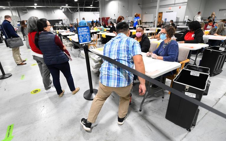 An election worker moves in to assist other workers as obervers at left look on as votes for President are recounted at the Gwinnett County elections office on Friday, Nov.13, 2020 in Lawrenceville. (JOHN AMIS FOR THE ATLANTA JOURNAL-CONSTITUTION)