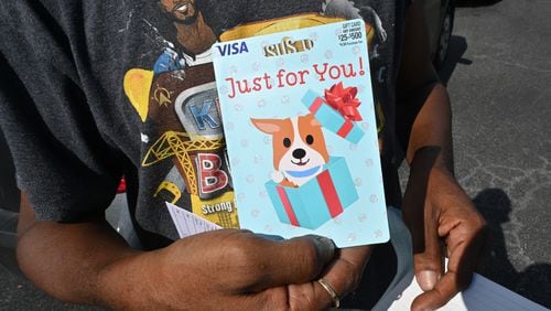 A DeKalb County resident shows off the $100 prepaid debit card he received after he got the COVID-19 vaccine shot during an event at The Gallery at South DeKalb on Saturday, August 13, 2021. (Hyosub Shin / Hyosub.Shin@ajc.com)
