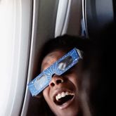 Kyle McSween, 9 from Atlanta, looks out the window during the solar eclipse on Delta Air Line’s flight along the eclipse path from Dallas to Detroit on Monday, April 8, 2024. (Natrice Miller/ Natrice.miller@ajc.com)