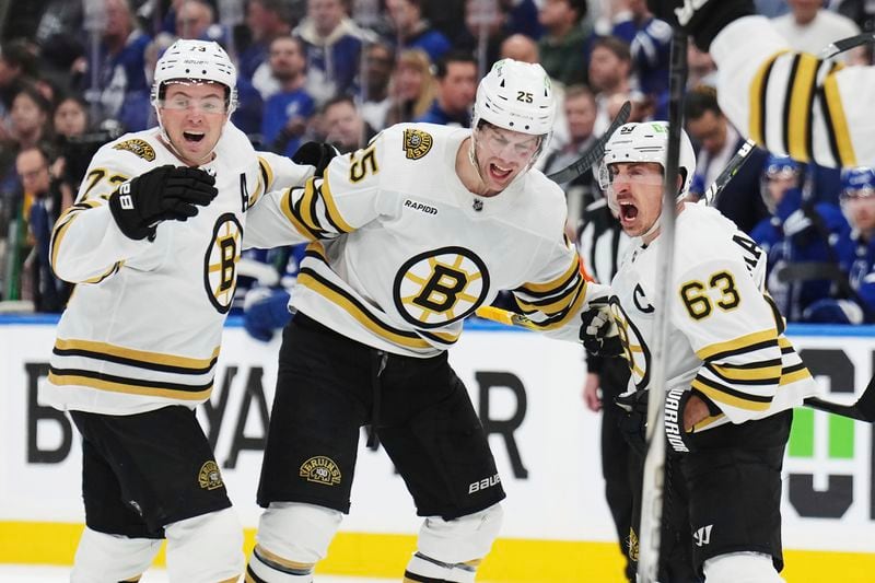 Boston Bruins' Brad Marchand (63) celebrates his goal against the Toronto Maple Leafs with Brandon Carlo and Charlie McAvoy during third period of action in Game 3 of an NHL hockey Stanley Cup first-round playoff series in Toronto on Wednesday, April 24, 2024. (Nathan Denette/The Canadian Press via AP)
