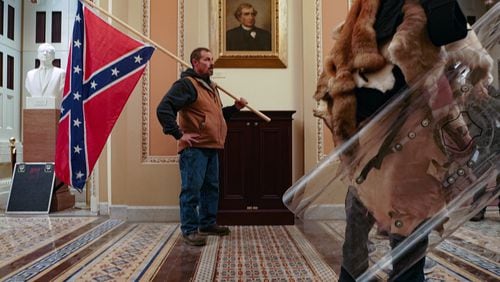 A supporter of President Donald Trump carries a Confederate battle flag inside the Capitol building in Washington, as a mob of his supporters protest the presidential election results, on Wednesday, Jan. 6, 2021. Historians said it was unnerving to see a man carry the flag inside the Capitol, something not even Confederate soldiers were able to do during the Civil War. (Erin Schaff/The New York Times)