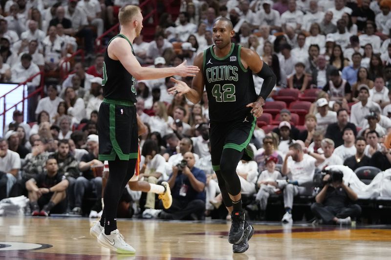 Boston Celtics center Al Horford (42) and forward Sam Hauser congratulate each other after a play during the second half of Game 3 of an NBA basketball first-round playoff series against the Miami Heat, Saturday, April 27, 2024, in Miami. (AP Photo/Wilfredo Lee)
