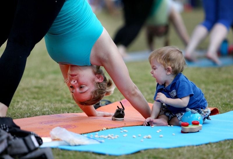 Stephani Jenkins, of Palm Beach Gardens, with her 13-month-old son Bradley, practices Vinyasa yoga at the Seventh Annual Yoga Day at the Meyer Amphitheatre in West Palm Beach, Fla., Sunday, February 24, 2013. (Gary Coronado/The Palm Beach Post)