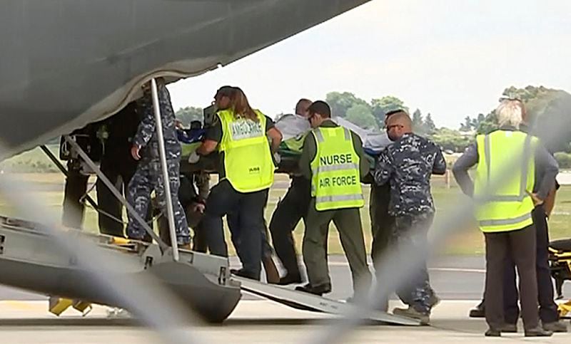 An injured tourist in the volcano eruption is carried Thursday to an Australian Air Force plane in Hamilton, New Zealand. New Zealand officials say they'll begin Friday to recover eight victims' bodies believed to remain on a small island since a volcanic explosion there earlier this week.