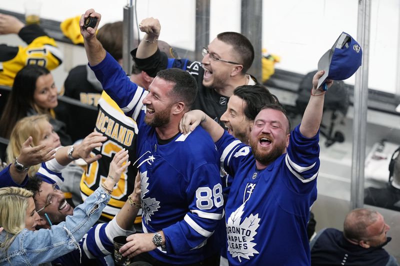 Toronto Maple Leafs fans react after catching a puck that went over the glass during the third period of Game 7 of an NHL hockey Stanley Cup first-round playoff series against the Boston Bruins, Saturday, May 4, 2024, in Boston. (AP Photo/Michael Dwyer)
