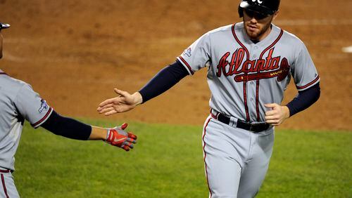 Atlanta Braves first baseman Freddie Freeman (5) is congratulated after scoring a run in the fourth inning against the Los Angeles Dodgers in game four of the National League divisional series playoff baseball game at Dodger Stadium.