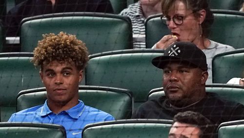 Druw Jones (left) sits with his dad, former Braves great Andruw Jones, during a game between Athletics and the Braves on Tuesday, June 7, 2022, in Atlanta. (AP Photo/John Bazemore)