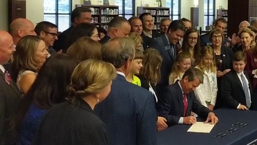 May 2, 2019, Marietta -- Gov. Brian Kemp, flanked by children, parents, lawmakers and educators, signs new dyslexia mandate during ceremony at Wheeler High School Thursday.