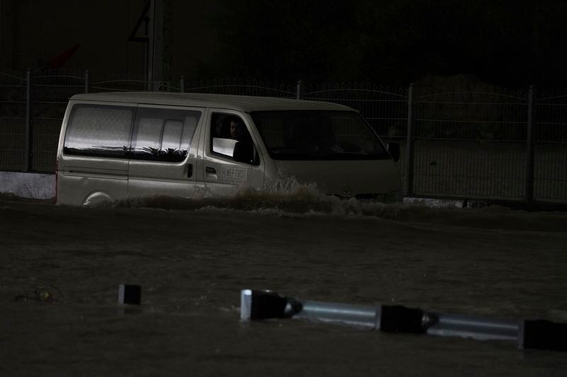 A van passes through standing water in Dubai, United Arab Emirates, Tuesday, April 16, 2024. Heavy rains lashed the United Arab Emirates on Tuesday, flooding out portions of major highways and leaving vehicles abandoned on roadways across Dubai. Meanwhile, the death toll in separate heavy flooding in neighboring Oman rose to 18 with others still missing as the sultanate prepared for the storm. (AP Photo/Jon Gambrell)