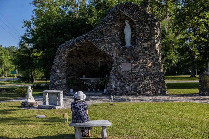 A parisioner sits near the grotto outside of Our Lady of Lourdes Catholic Church in Port Wentworth.