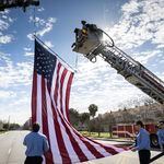 Members  of the Savannah Fire Department lift a large American flag into place before a motorcade carrying the remains of U.S. Army Reservist Sgt. Breonna Moffett passes, Thursday, Feb. 15, 2024, Savannah, Ga. Moffett and two other solders were killed in Jordan during a drone attack. (AJC Photo/Stephen B. Morton)