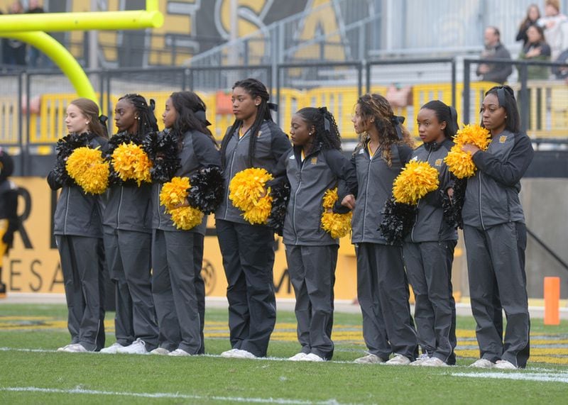 Some Kennesaw State cheerleaders link arms while on the field during the national anthem at the Veterans Day game on Saturday, Nov. 11, 2017. Some of the cheerleaders had come under fire for taking a knee during the national anthem at recent home games, and recently the cheerleaders had to be in a tunnel during the national anthem. 