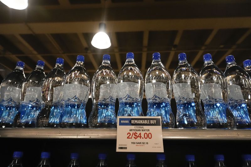 Bottled water in plastic bottles line the shelves at a grocery store in New Orleans, Wednesday, April 17, 2024. People are increasingly breathing, eating and drinking tiny particles of plastic, however, there are simple things people can do at the grocery store if they want to use less plastic. (AP Photo/Gerald Herbert)