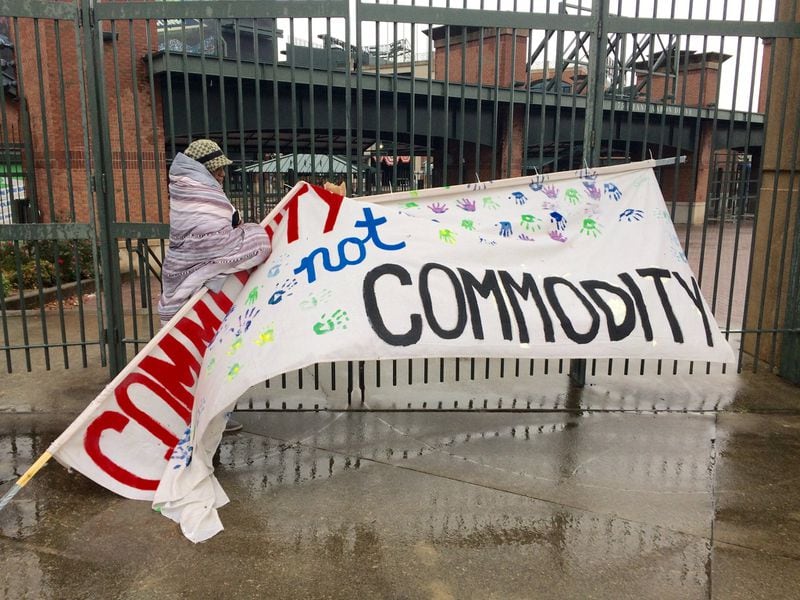 Peoplestown resident Sherise Brown fixes a sign that reads “Community not Commodity” that had been knocked down by the weather outside Turner Field in 2017. J. Scott Trubey/strubey@ajc.com