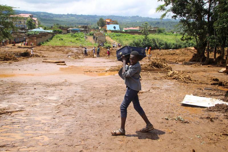 A child carrying a suitcase, walks, after a dam burst, in Kamuchiri Village Mai Mahiu, Nakuru County, Kenya, Monday, April 29, 2024. Police in Kenya say at least 40 people have died after a dam collapsed in the country's west. (AP Photo/Patrick Ngugi)