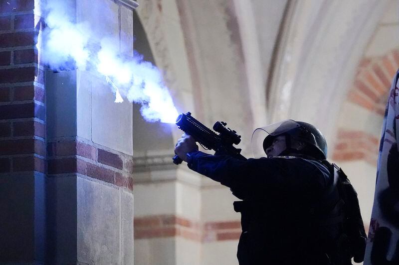 FILE - A police officer launches a smoke bomb on the UCLA campus during a raid on a pro-Palestinian encampment Thursday, May 2, 2024, in Los Angeles. (AP Photo/Ryan Sun, File)
