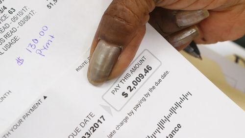 Toby Jennings of Lithonia holds her water bill of $2009.49 while DeKalb CEO Mike Thurmond updated residents about the depth of the county's remaining water billing problems during his third public update on June 29.  Curtis Compton/ccompton@ajc.com