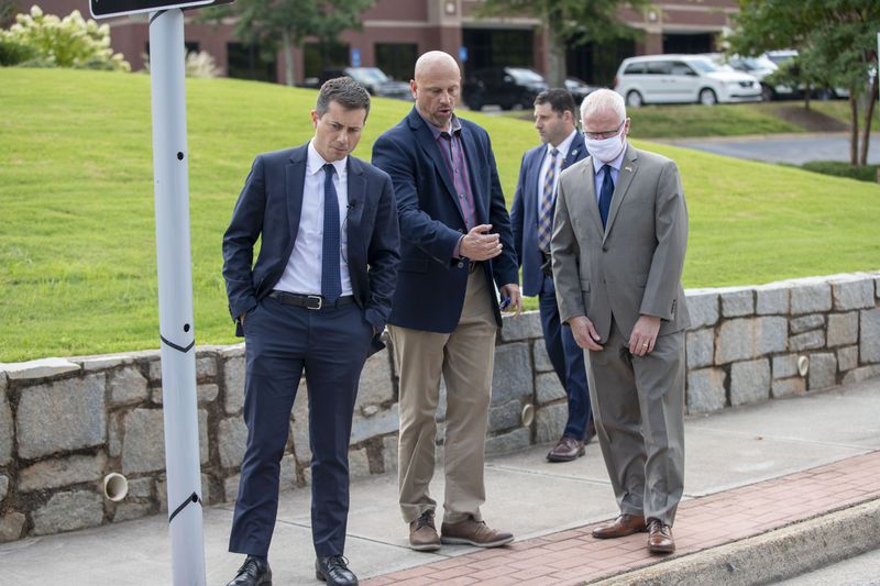 U.S. Transportation Secretary Pete Buttigieg, left, receives an overview Friday of a solar roadway that was installed along Technology Parkway in Peachtree Corners.  (Alyssa Pointer/Atlanta Journal Constitution)