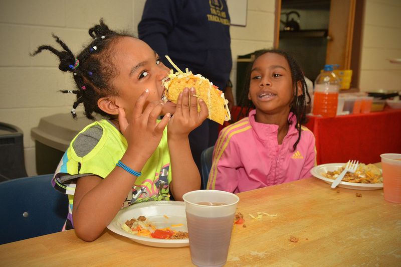Kailani Carter (left) and her sister Alicia Carter enjoy tacos at Hagar’s House in Decatur. Hagar’s House, part of Decatur Cooperative Ministry, is an emergency shelter providing up to 90 days of shelter and support for families with children. Every night, volunteers arrive at Hagar’s House loaded with dinner. CHRIS HUNT / SPECIAL