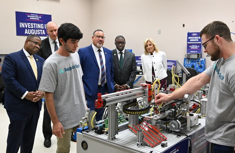 First Lady Jill Biden (background right) and other officials (background from left) Augusta Mayor Garnett Johnson, U.S. Deputy Secretary of Energy David Turk , U.S. Secretary of Education Miguel Cardona and Augusta Technical College President Jermaine Whirl watch as students Patrick Kling (foreground left) and Dustin Phillips  demonstrate during America Workforce Hub tour at Augusta Technical College, Tuesday, July 18, 2023, in Augusta, Georgia. First Lady Jill Biden and U.S. Secretary of Education Miguel Cardona meet with local officials and key stakeholders leading the Investing in America Workforce Hub in Augusta, Georgia to highlight to how Bidenomics is delivering investments and jobs to communities across the country. (Hyosub Shin / Hyosub.Shin@ajc.com)