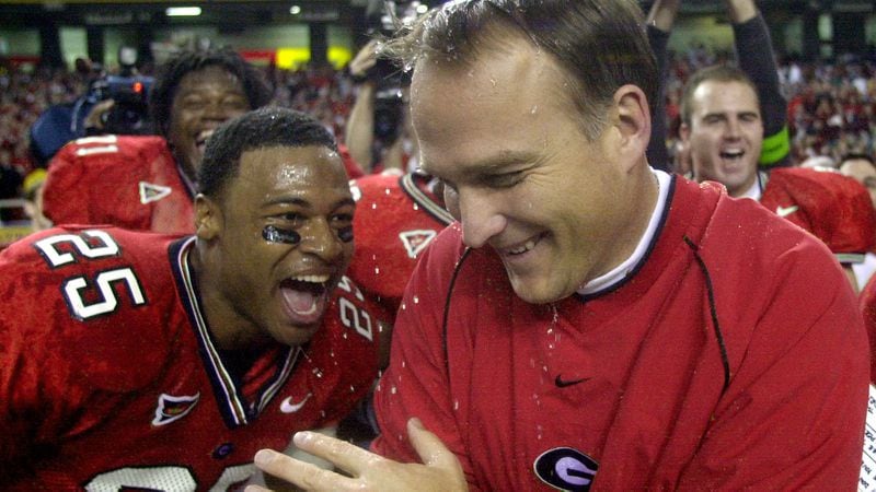 Georgia head coach Mark Richt celebrates with Michael Johnson (25) after he was doused with water as the Bulldogs beat Arkansas 30-3 in the SEC Championship Saturday, Dec. 7, 2002, at the Georgia Dome in Atlanta. 