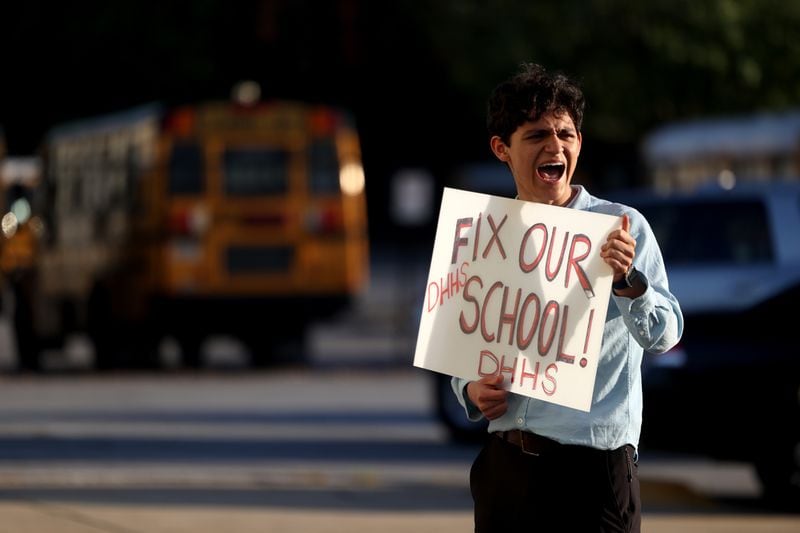Druid Hills sophomore Santiago Gonzalez-Cassavoy holds a sign reading, “fix our school,” outside of the DeKalb County Board of Education meeting at the district's headquarter in Stone Mountain, Georgia, headquarters on April 18, 2022. (Jason Getz / Jason.Getz@ajc.com)