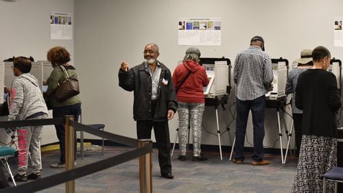 Volunteer Alfred Leblanc (center) directs early voters at the Gwinnett County Voter Registrations and Elections Office in Lawrenceville on Thursday, October 18, 2018. HYOSUB SHIN / HSHIN@AJC.COM