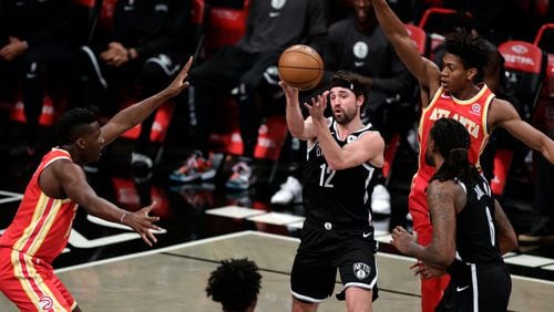 Brooklyn Nets guard Joe Harris (12) passes the ball in front of Atlanta Hawks center Clint Capela, left, during the first half of an NBA basketball game Friday, Jan. 1, 2021, in New York. (AP Photo/Adam Hunger)
