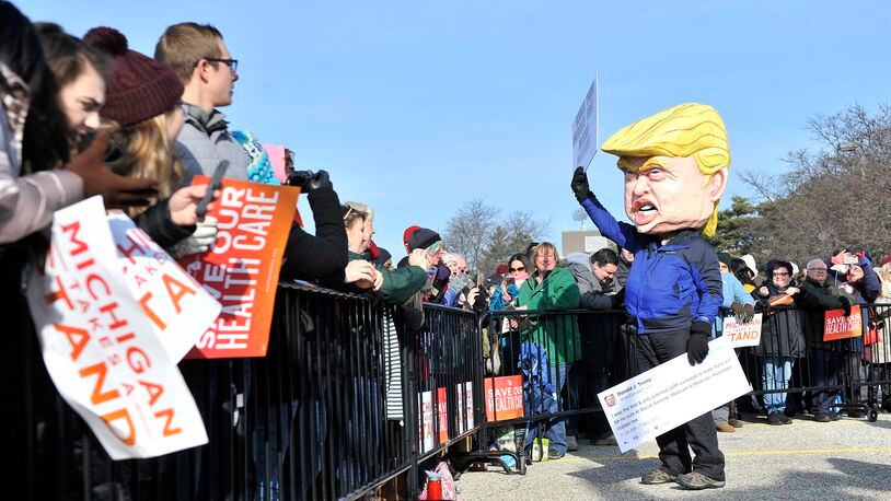 In a Sunday, Jan. 15, 2017 photo, A person dressed as Donald Trump waves before a rally for health care at Macomb Community College in Warren, Mich. Thousands of people showed up in freezing temperatures on Sunday in Michigan to hear Sanders denounce Republican efforts to repeal President Barack Obama's health care law, one of dozens of rallies Democrats staged across the country to highlight opposition. (Robin Buckson/The Detroit News via AP)