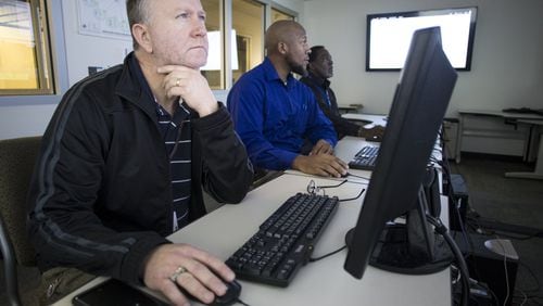 Systems engineers (from left) Andy Clement, 47, Corey English, 42, and Jerry Thomas, 63, monitor screens at the DeKalb County school district’s William Bradley Bryant Center for Technology in Decatur on Wednesday, Dec. 6, 2017. (CASEY SYKES, CASEY.SYKES@AJC.COM)