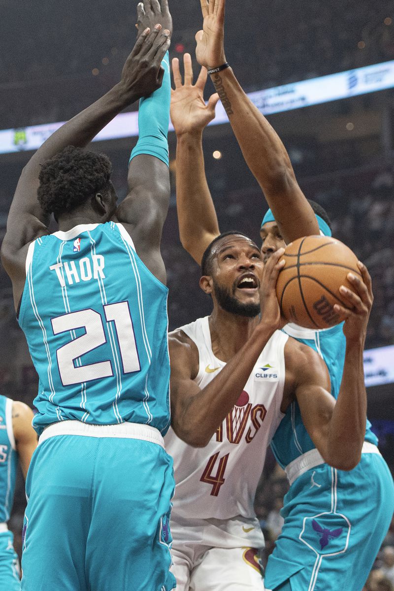 Cleveland Cavaliers' Evan Mobley (4) squeezes between Charlotte Hornets' JT Thor (21) and Marques Bolden, right, during the first half of an NBA basketball game in Cleveland, Sunday, April 14, 2024. (AP Photo/Phil Long)