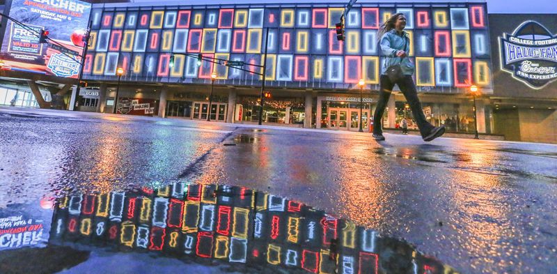 File photo: Jennifer Toland from Boise, Idaho crosses Marietta Street in front of the colorful facade of the College Football Hall of Fame in downtown Atlanta earlier this year. JOHN SPINK/JSPINK@AJC.COM
