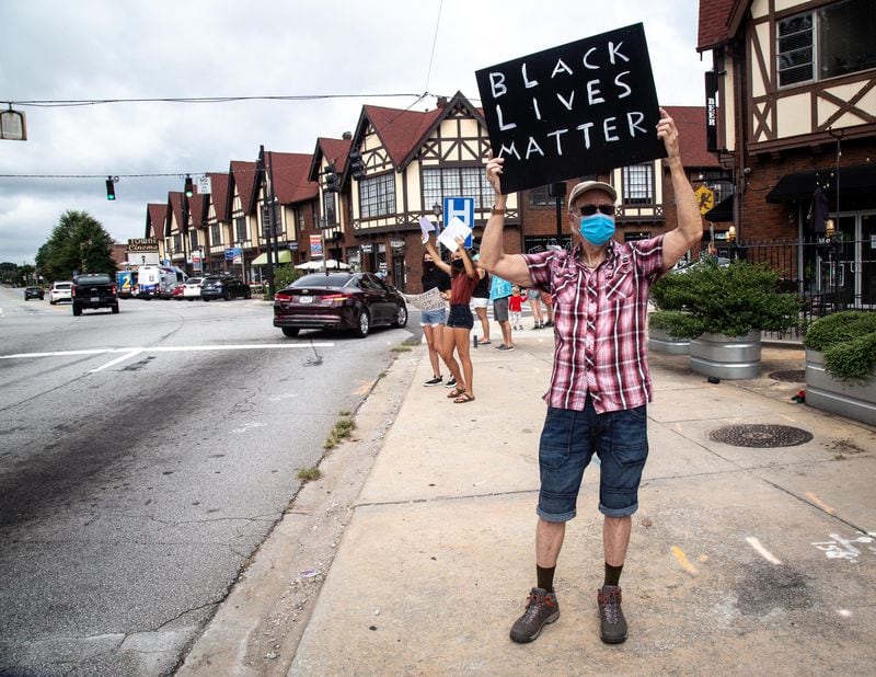  An Avondale Alliance for Racial Justice protester Frank Mullins holds up a sign as cars drive by in Avondale Estates's downtown strip Saturday, August 29, 2020. STEVE SCHAEFER FOR THE ATLANTA JOURNAL-CONSTITUTION